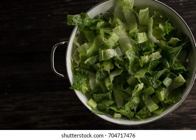 Washed Romaine Lettuce In Colander On Dark Wood Table