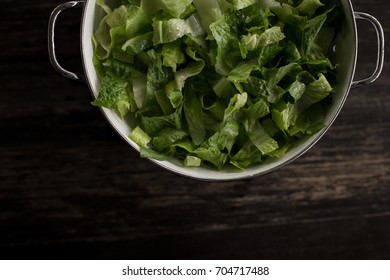 Washed Romaine Lettuce In Colander On Dark Wood Table