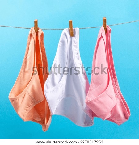 washed women's panties made of cotton with clothespins hanging on a rope on a blue background
