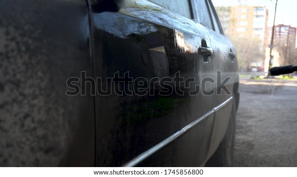 Washes away dirt from a car with a high pressure\
water jet closeup. Special detergent for car wash. Washes a car in\
front of the house.