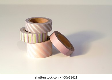 Washi tape rolls, masking tape rolls in pile. Pink tones and stripes motifs. Isolated on white background