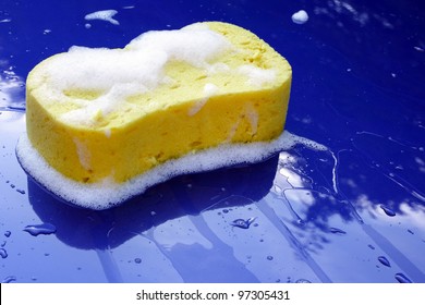 Washing Bonnet Of Blue Car With A Sponge