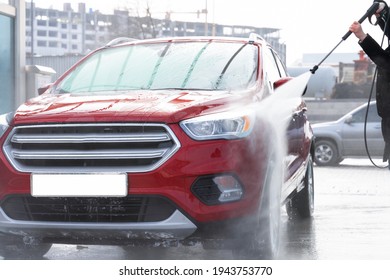 washing car at autowash . Car wash. red machine under the pressure of water at a car wash. car in foam. woman washing automobile
