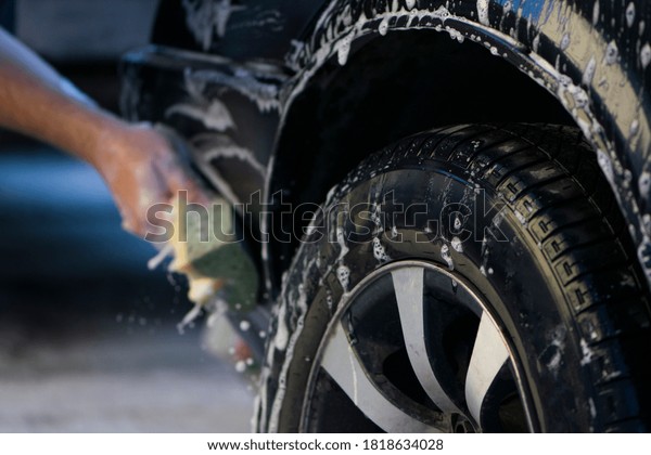 washing the car by hand with a sponge in foam\
close-up. washes new car alloy silver rims, tires, soapy sponge,\
car cleaning, car maintenance, shiny, sparkling, water, foam,\
rubbing, shine,\
close-up