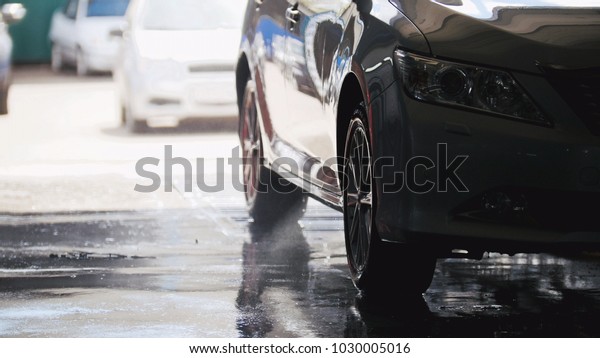 Washing a\
car in the suds by water hoses,\
silhouette