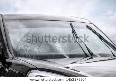 Washing car windscreen with wipers and liquid, closeup