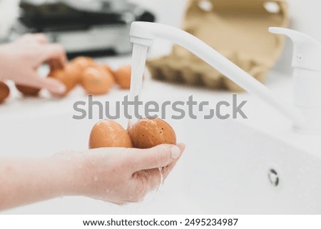 Washing chicken brown organic eggs under running water in sink, health care and salmonella protection concept
