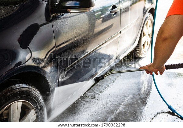 Washing and cleaning car in self service car wash\
station. Car washing using high pressure water in Bucharest,\
Romania, 2020