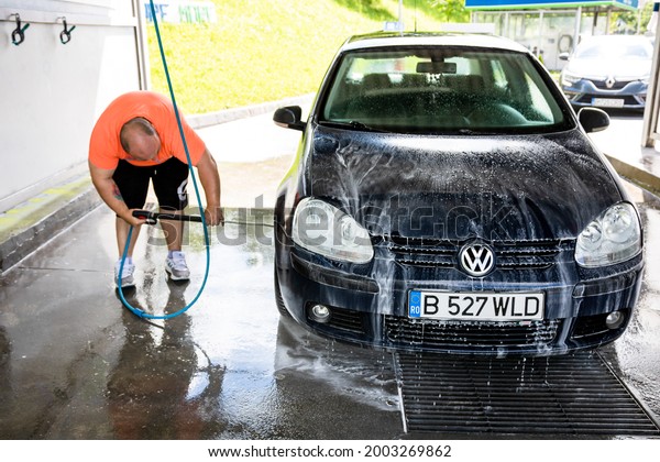Washing and cleaning car in self service car wash\
station. Car washing using high pressure water in Bucharest,\
Romania, 2021
