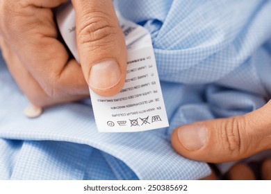 Washing, Clothes, Housework And People - Close Up Of Male Hands Holding Shirt And Label With Instructions