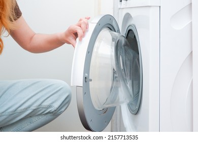 Washing clothes. A woman is loading a washing machine. Light interior. Close-up. Woman Putting Cloth In Washing Machine At Home - Powered by Shutterstock