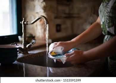 Washing the dishes in the kitchen and wasting water. Global warming concept.