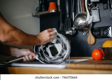 washing dishes. male hands in foam washes the frying pan with a detergent and sponge in the kitchen of the house. - Shutterstock ID 746370664