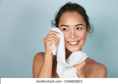 Washing Face. Closeup Of Woman Cleaning Skin With Towel Portrait. Beautiful Asian Girl Model Wiping Facial Skin With Soft Facial Towel, Removing Makeup. High Quality Studio Shot