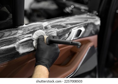 Washing with foam and detergent using a brush on the inner surface of the car door. Car detailing service.