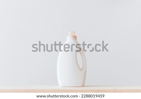 Washing gel liquid laundry detergent or fabric softener on a wooden table against a light white background with copy space.