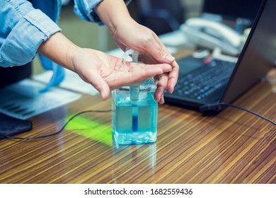 Washing Hands With Alcohol Sanitizer To Avoid Contamination With Coronavirus Covid-19. Washing Hand With Blurry Laptop And Phone In Office. The Concept Of Cleaning In Office To Protect Covid 19.