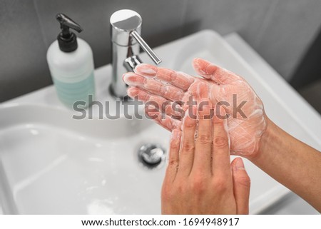 Washing hands rubbing soap in palm lathering up foam bubbles for corona virus COVID-19 prevention, hygiene to stop spreading coronavirus. Woman handwashing step at bathroom sink.