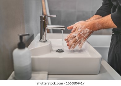 Washing hands with soap and hot water at home bathroom sink man cleansing hand hygiene for coronavirus outbreak prevention. Corona Virus pandemic protection by washing hands frequently. - Powered by Shutterstock