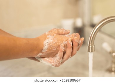 Washing hands with soap under running water in bathroom sink. Hygiene, cleanliness, handwashing, health, sanitation, care - Powered by Shutterstock