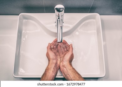Washing hands with soap at work bathroom sink man hand care hygiene for coronavirus outbreak prevention. Corona Virus pandemic precaution by washing hands frequently for 20 seconds. - Shutterstock ID 1672978477