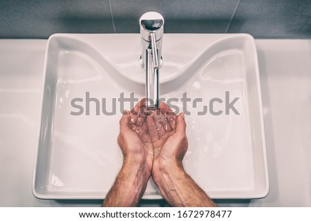 Washing hands with soap at work bathroom sink man hand care hygiene for coronavirus outbreak prevention. Corona Virus pandemic precaution by washing hands frequently for 20 seconds.