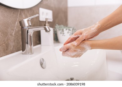 Washing hands under the flowing water tap. Washing hands rubbing with soap for corona virus prevention, hygiene to stop spreading corona virus in or public wash room. Hygiene concept hand detail. - Shutterstock ID 2086039198