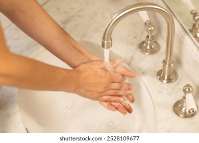 Washing hands under running water in bathroom sink, maintaining hygiene. cleanliness, handwashing, soap, sanitation, health, prevention - Powered by Shutterstock