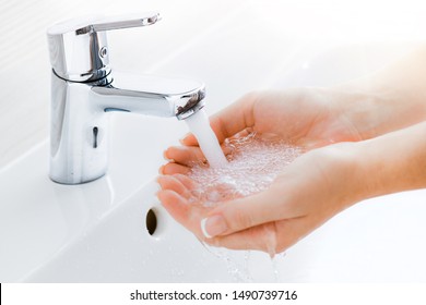 Washing hands under the water tap or faucet without soap. Hygiene concept detail. Beautiful hand and water stream in bathroom. New modern basin cleaning. - Shutterstock ID 1490739716