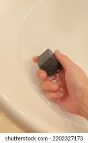 Washing Hands In A White Sink With Black Soap Bar During Covid