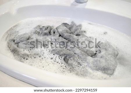 Washing a jumper in the basin or sink. Washing clothes by hand.  The concept of how to wash a jumper and look after it.
