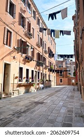 Washing Lines Across An Alley In Venice, Italy. Laundry Hanging On A Clothes Line Between City Buildings. Clothes Lines Between Old Brick Houses In Venice.