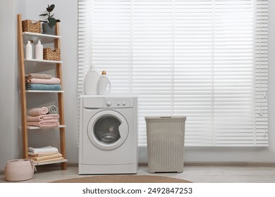 Washing machine, detergents, towels and basket in laundry room - Powered by Shutterstock