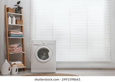 Washing machine, detergents, towels and shelving unit in laundry room - Powered by Shutterstock