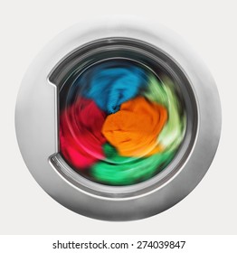 Washing Machine Door With Rotating Garments Inside. Focus In The Center Of Dirty Laundry And Washing Machine On The Frame