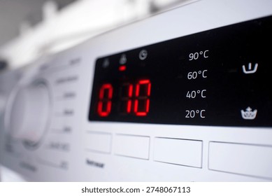 Washing machine electronic display panel showing remaining time for laundry cycle and selectable temperature settings, highlighting household appliance technology and everyday home chores