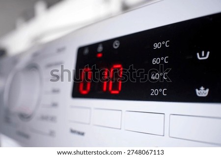 Washing machine electronic display panel showing remaining time for laundry cycle and selectable temperature settings, highlighting household appliance technology and everyday home chores