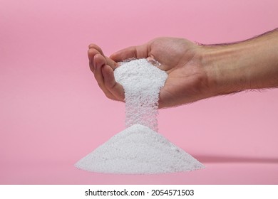Washing powder on a pink background. Detergent for washing clothes. Washing powder pouring out of a man's hand