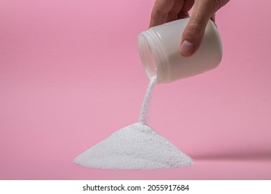 Washing powder on a pink background. Detergent for washing clothes. Washing powder is poured out of the container - Shutterstock ID 2055917684