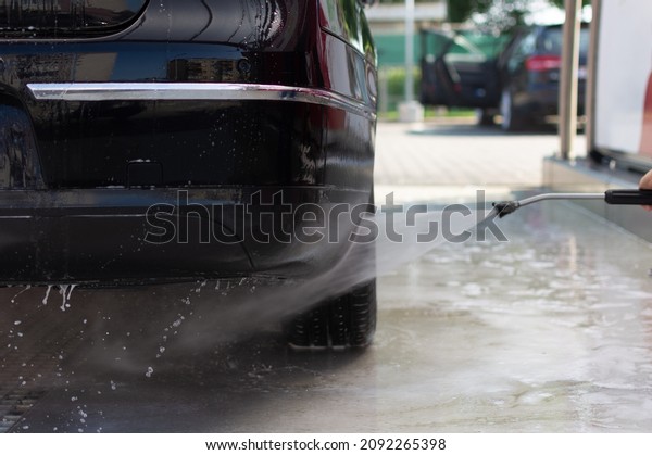 washing the rear bumper\
of the black car