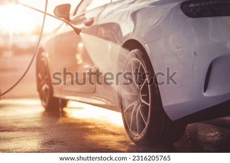 Washing rims at a manual car wash during sunset.