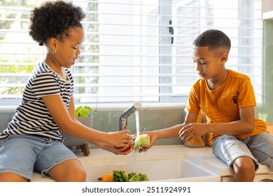 Washing vegetables together, young brother and sister in kitchen preparing healthy meal. Cooking, family, healthy eating, teamwork, nutrition, bonding - Powered by Shutterstock