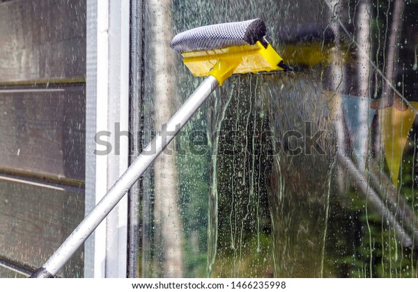 washing Windows, cleaning glasses and surfaces.\
yellow-white telescopic washing brush cleanly washes and wipes the\
Windows of the house.
