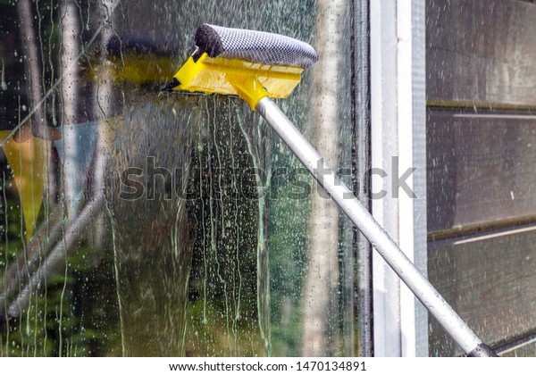 washing Windows, cleaning glasses and surfaces.\
yellow-white telescopic washing brush cleanly washes and wipes the\
Windows of the house.