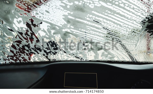 Washing windshield screen of modern car, view from\
inside 