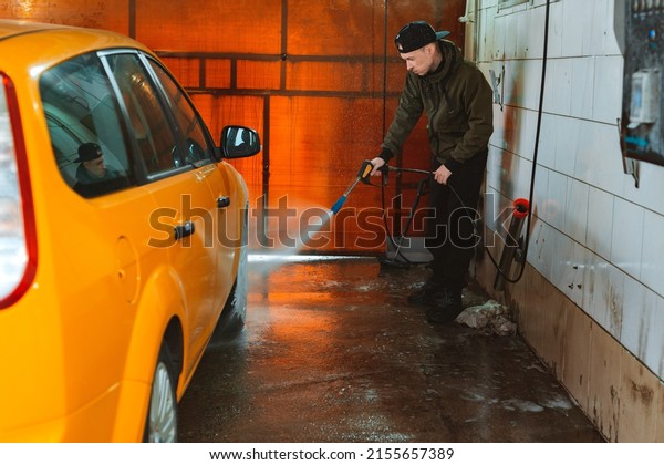 Washing a yellow car at a contactless\
self-service car wash. Washing a sedan car with foam and\
high-pressure water. Spring cleaning at the car\
wash.