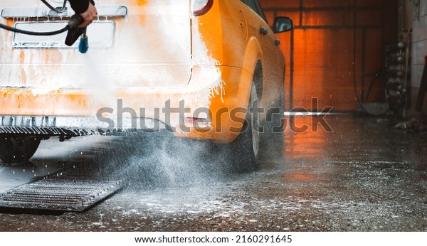 Washing a yellow car at a contactless\
self-service car wash. Washing a sedan car with foam and\
high-pressure water. Spring cleaning at the car\
wash.