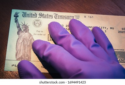 WASHINGTON DC - APRIL 5. 2020: United States Treasury check being held by rubber glove illustrates US Government coronavirus economic impact payment sent to US taxpayers for relief.