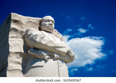 WASHINGTON DC - AUGUST, 2018: The portrait of Dr Martin Luther King, Jr carved from white stone at the memorial in his name stands with arms crossed looking out into bright blue sky.