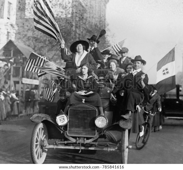 Washington, DC, celebration of the Armistice ending\
World War 1, Nov. 1918. An overloaded car of eleven happy men and\
women wave American\
flags